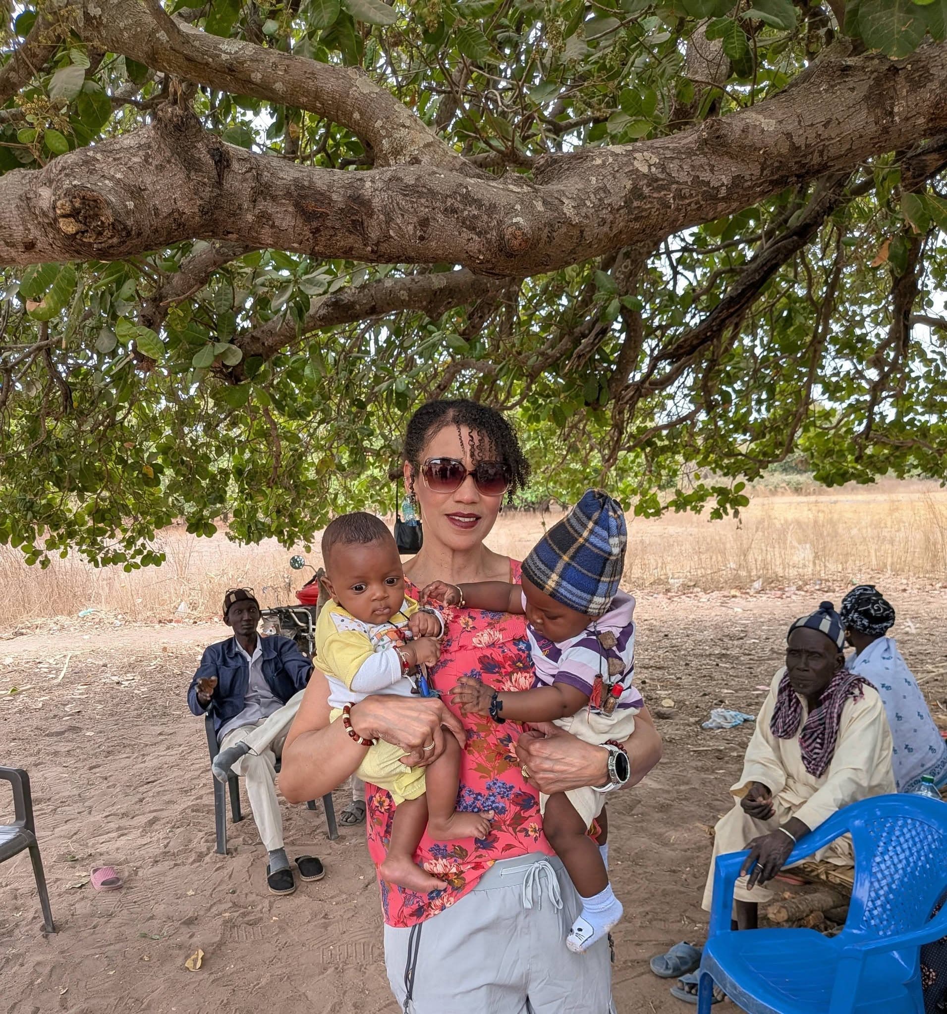 Heart In Heaven founder Angelique McGlotten holding two babies while visiting children in the community in Senegal